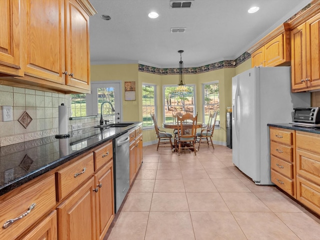 kitchen with decorative light fixtures, sink, dark stone counters, ornamental molding, and stainless steel dishwasher