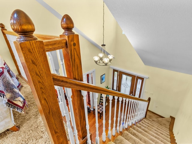 stairs with high vaulted ceiling, carpet, and an inviting chandelier