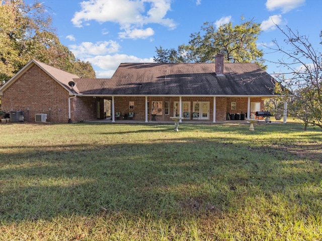 back of property with central AC unit, a patio area, and a lawn