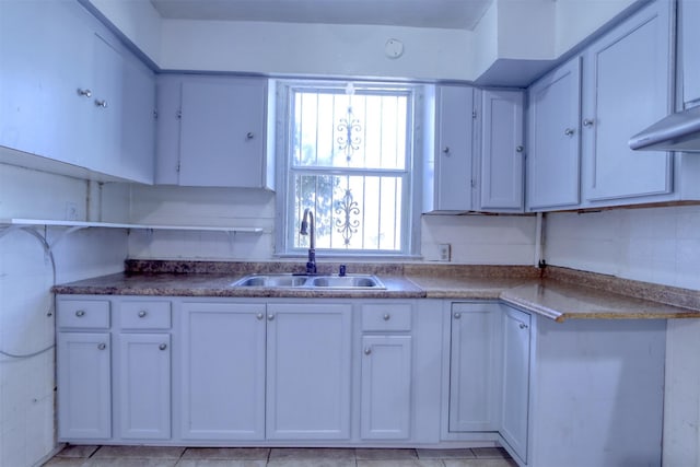 kitchen with light tile patterned floors, sink, and white cabinets