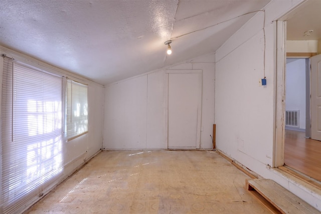 spare room with vaulted ceiling and a textured ceiling