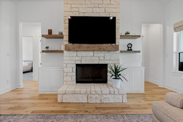 living room with built in shelves, a fireplace, and light hardwood / wood-style floors