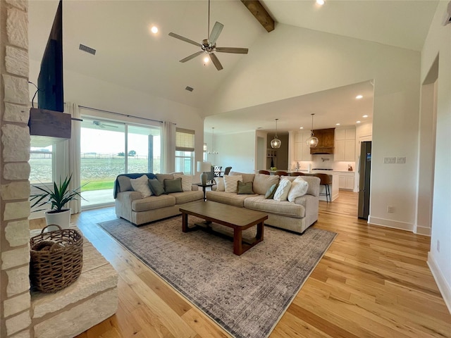 living room featuring ceiling fan, beam ceiling, light hardwood / wood-style floors, and high vaulted ceiling