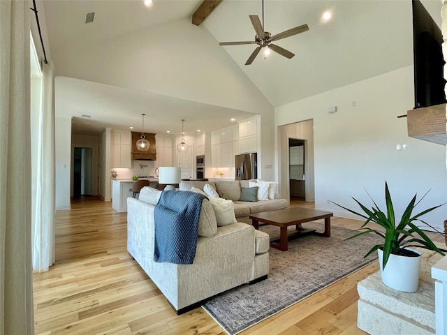 living room featuring beamed ceiling, ceiling fan, light hardwood / wood-style floors, and high vaulted ceiling