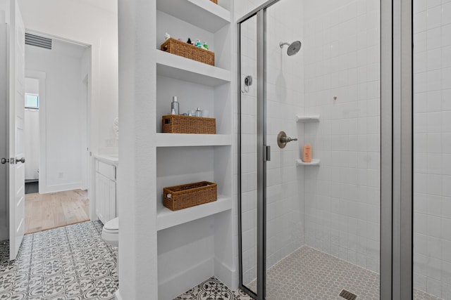 bathroom featuring tile patterned floors, toilet, a shower with door, and vanity