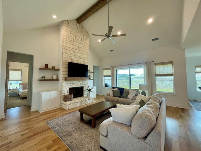 living room featuring beamed ceiling, high vaulted ceiling, a fireplace, and light hardwood / wood-style floors