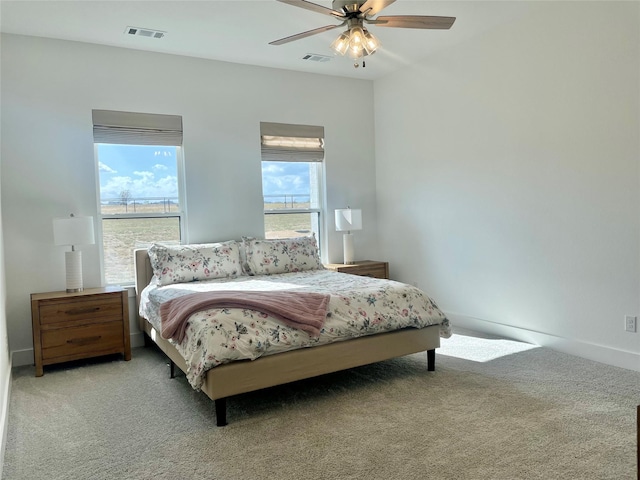 bedroom with ceiling fan, light colored carpet, and multiple windows