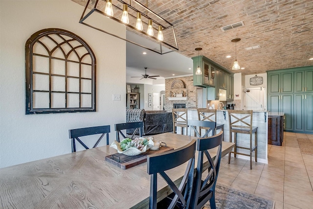 tiled dining area featuring brick ceiling, a brick fireplace, and ceiling fan