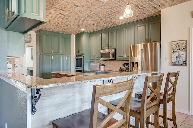 kitchen featuring kitchen peninsula, brick ceiling, light stone counters, green cabinetry, and stainless steel appliances