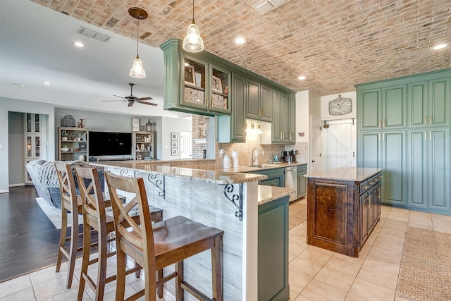 kitchen with pendant lighting, brick ceiling, green cabinets, light stone countertops, and kitchen peninsula