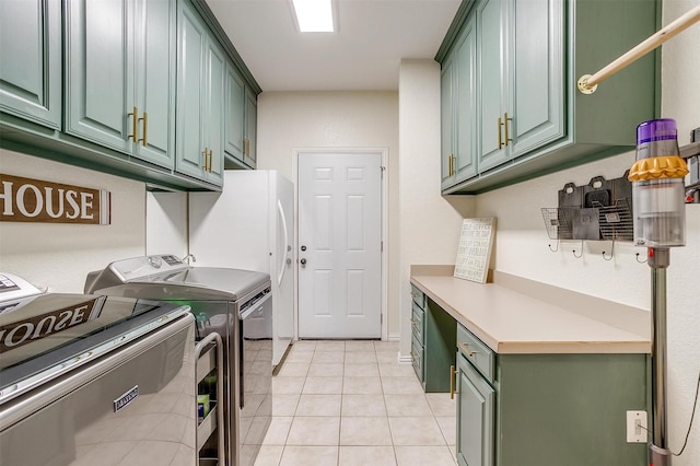 laundry area with cabinets, light tile patterned floors, and washer and clothes dryer