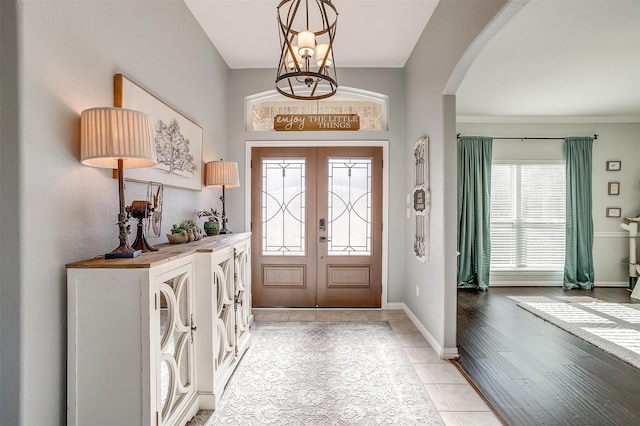 entrance foyer featuring a notable chandelier, french doors, and light tile patterned flooring