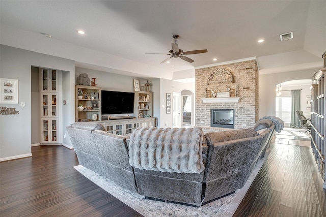 living room with ceiling fan, dark hardwood / wood-style flooring, and a brick fireplace