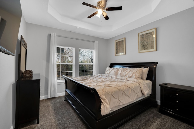 carpeted bedroom with ceiling fan and a tray ceiling