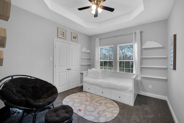 carpeted bedroom featuring ceiling fan, a tray ceiling, and a closet