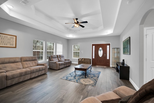 living room with a tray ceiling, wood-type flooring, and ceiling fan