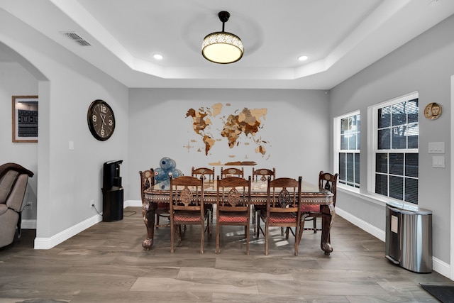 dining room with a tray ceiling and wood-type flooring