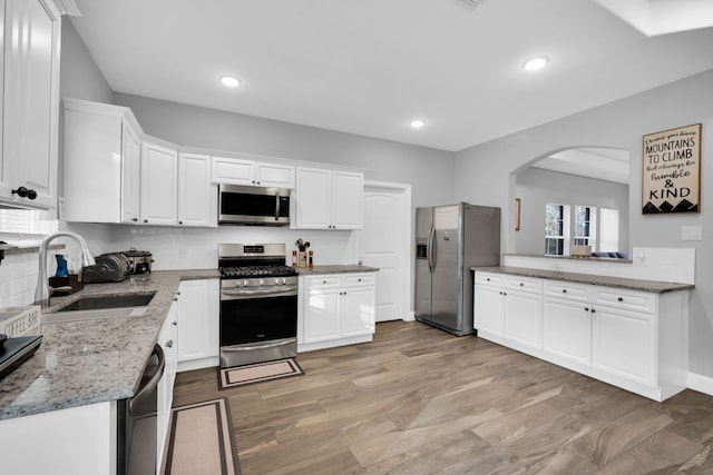 kitchen featuring white cabinetry, sink, stainless steel appliances, light stone countertops, and light hardwood / wood-style flooring