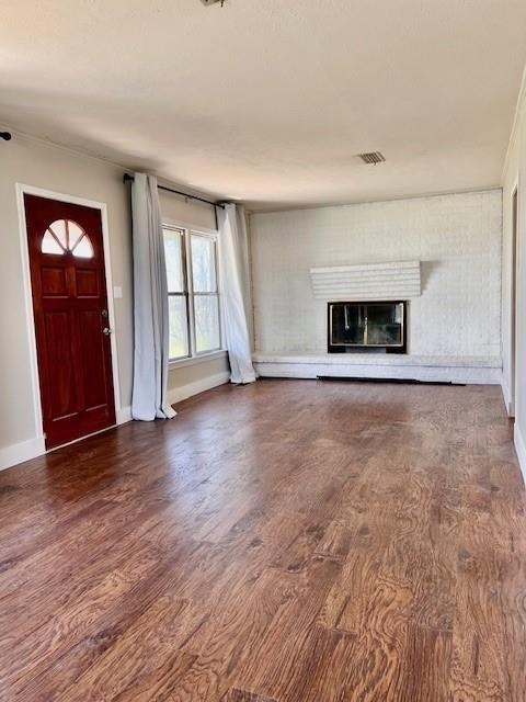 unfurnished living room featuring dark wood-type flooring and a fireplace