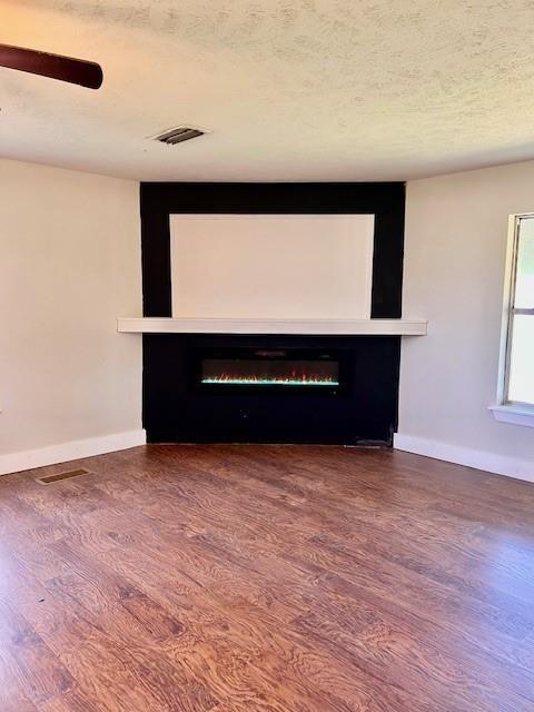 unfurnished living room featuring hardwood / wood-style flooring and a textured ceiling