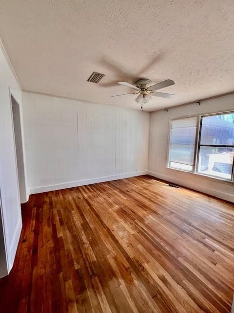 empty room with hardwood / wood-style flooring, ceiling fan, and a textured ceiling