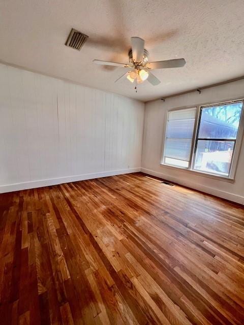 empty room with ceiling fan, hardwood / wood-style floors, and a textured ceiling