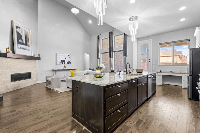 kitchen featuring dark wood finished floors, a glass covered fireplace, a sink, and freestanding refrigerator