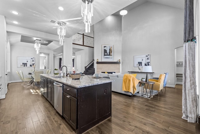 kitchen with dark wood-style floors, a sink, a stone fireplace, and dark brown cabinets