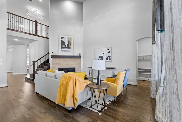 living area featuring baseboards, a fireplace, arched walkways, and wood finished floors