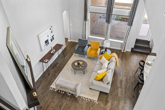 living room with arched walkways, wood finished floors, and baseboards