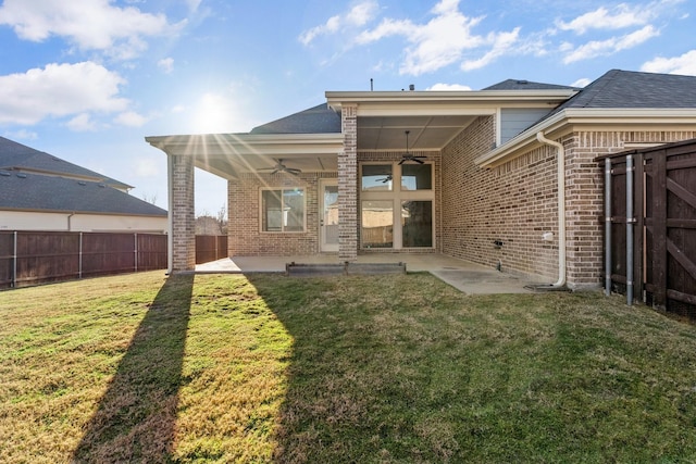 rear view of house with brick siding, a yard, a patio, a ceiling fan, and a fenced backyard