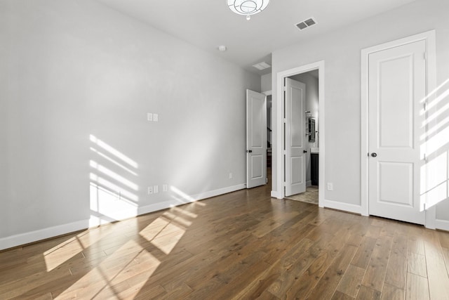 unfurnished bedroom with hardwood / wood-style floors, visible vents, and baseboards