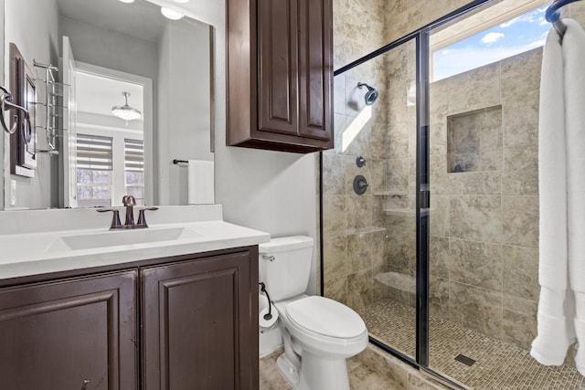 bathroom featuring toilet, a shower stall, and vanity