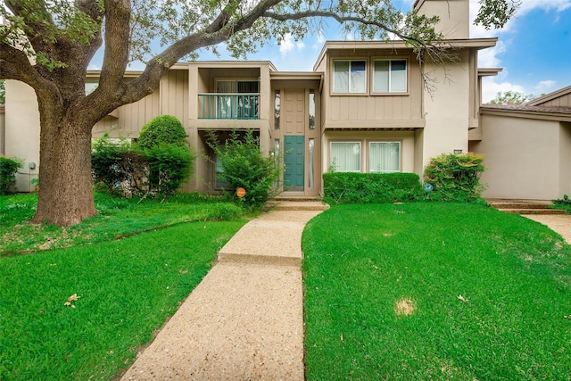 view of property featuring a balcony and a front lawn