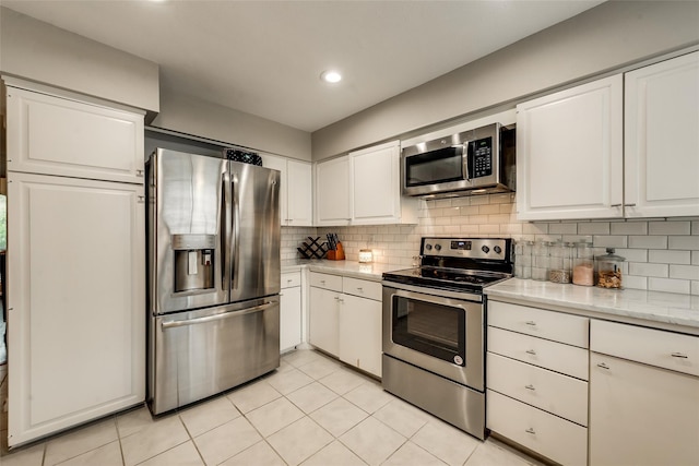 kitchen with backsplash, white cabinets, and appliances with stainless steel finishes