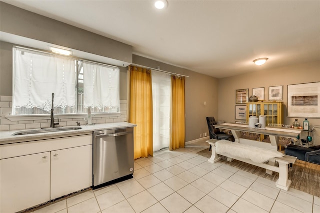 kitchen with white cabinetry, dishwasher, sink, backsplash, and light tile patterned floors