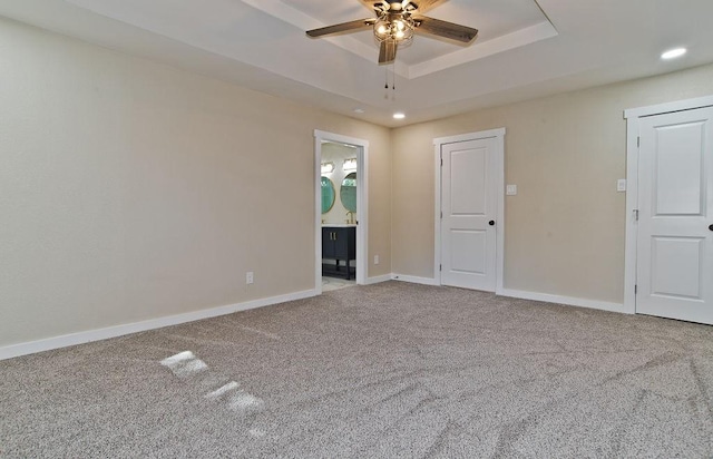 spare room with ceiling fan, carpet flooring, and a tray ceiling