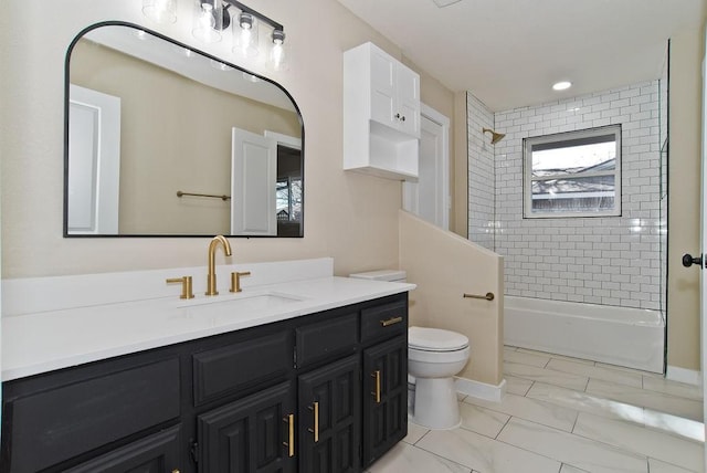 full bathroom featuring vanity, tiled shower / bath, and toilet