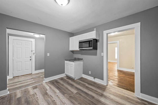 kitchen featuring wood-type flooring and white cabinets