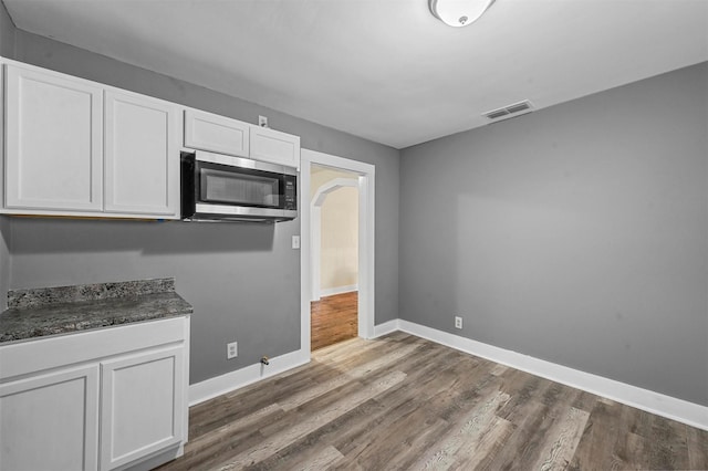 kitchen featuring white cabinetry, dark stone counters, and dark wood-type flooring