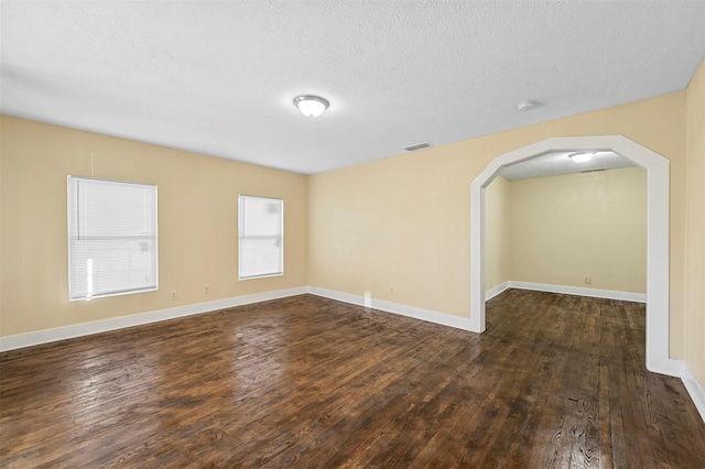 empty room with dark wood-type flooring and a textured ceiling