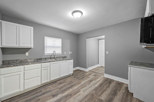 kitchen featuring hardwood / wood-style flooring, white cabinetry, and sink