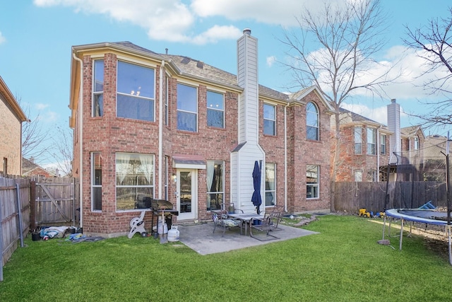 rear view of house featuring a trampoline, a yard, and a patio area