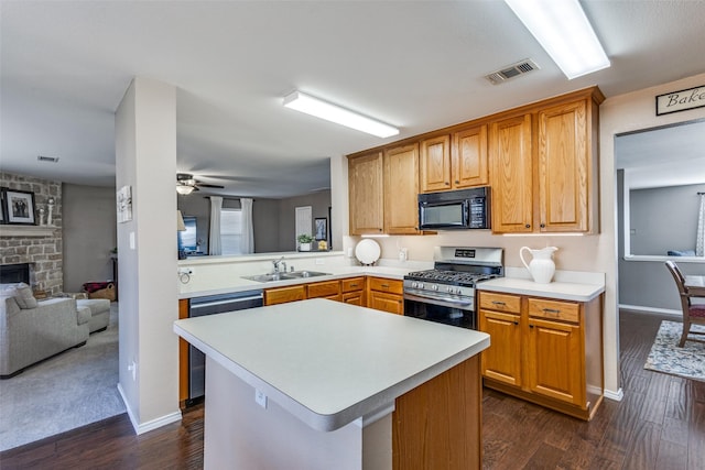 kitchen with sink, stainless steel appliances, a fireplace, dark hardwood / wood-style flooring, and kitchen peninsula