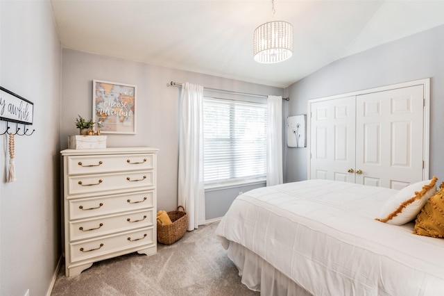 bedroom featuring vaulted ceiling, light carpet, a notable chandelier, and a closet