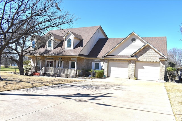 cape cod home with a shingled roof, concrete driveway, an attached garage, a porch, and brick siding