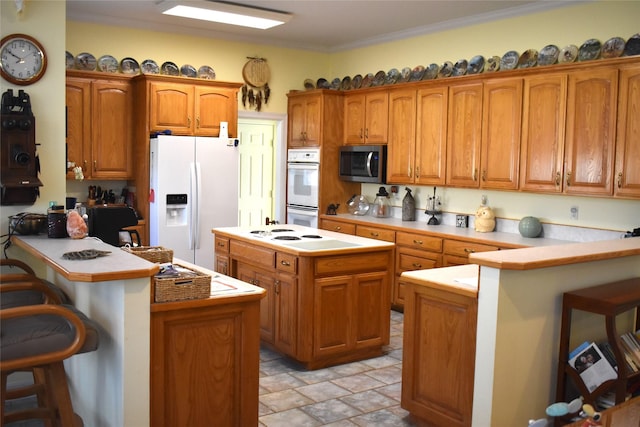 kitchen with ornamental molding, white appliances, a peninsula, and a kitchen breakfast bar