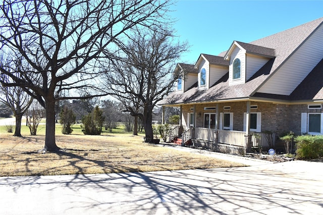 view of property exterior featuring brick siding, a porch, and a shingled roof