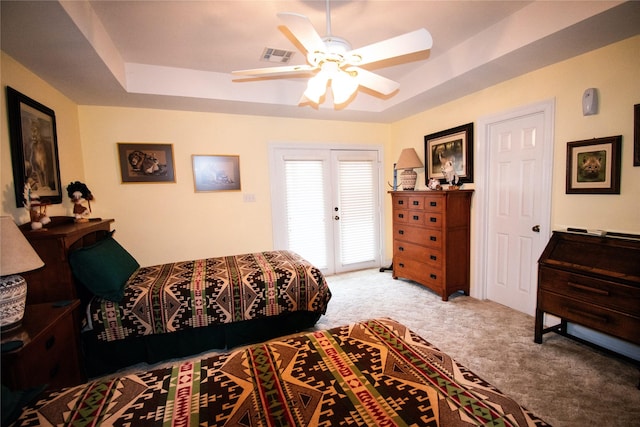 bedroom featuring a tray ceiling, carpet flooring, visible vents, and a ceiling fan