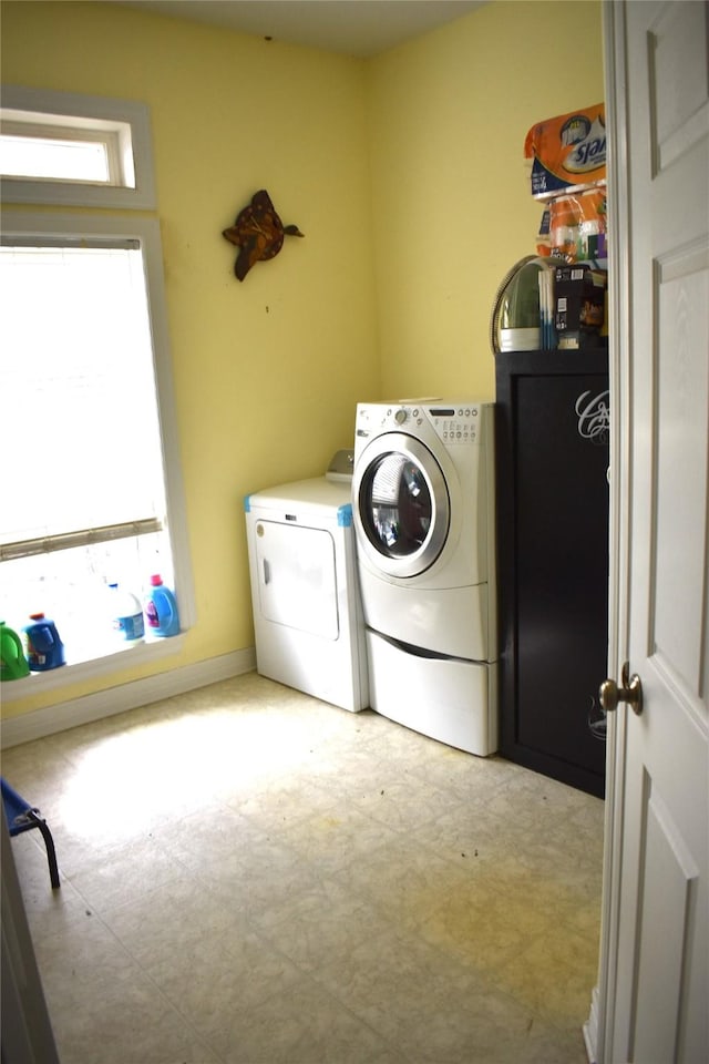 laundry area with a healthy amount of sunlight, laundry area, washer and clothes dryer, and light floors